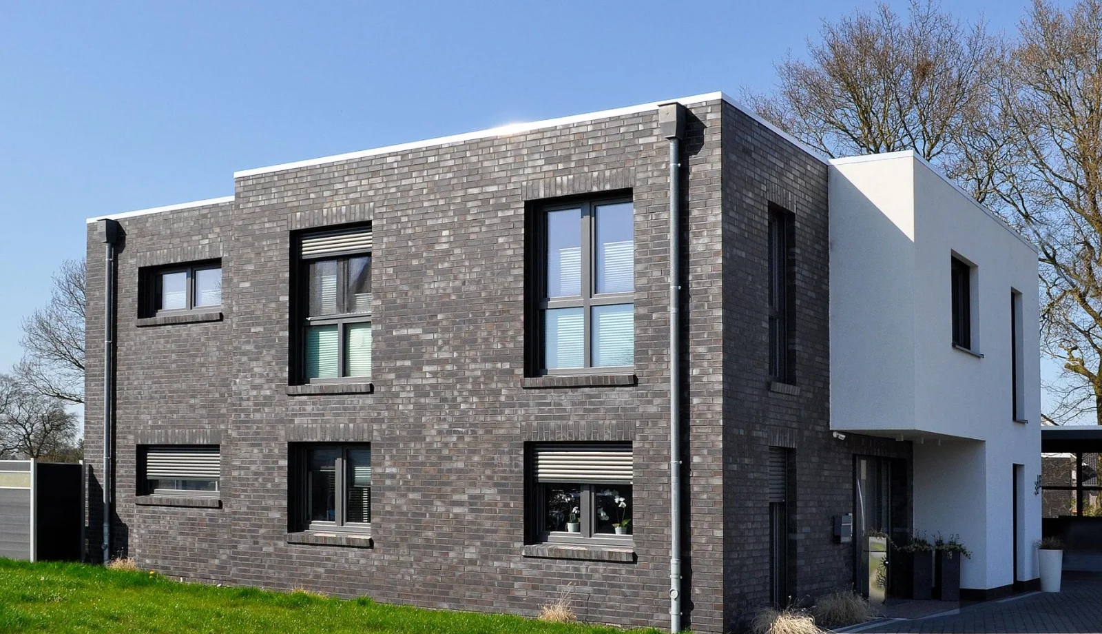 Modernes Haus mit dunkler Klinkerfassade und weißem Putz-Anbau